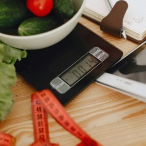 A bowl of fresh vegetables on a kitchen scale with measurement tools, depicting a healthy lifestyle.